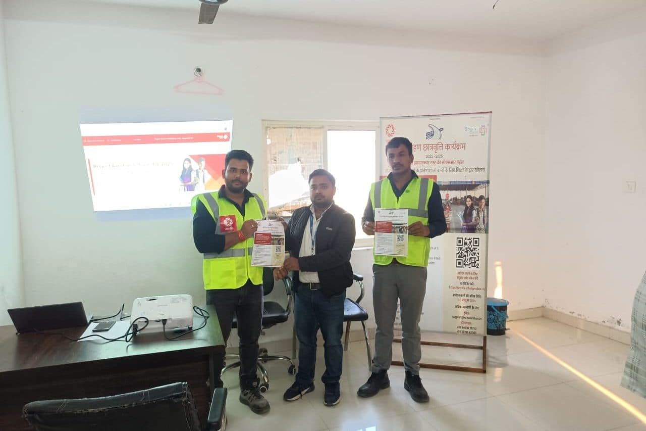 Three men, two of them in high-visibility vests, holding programme leaflets beside an Aarohan banner in an office